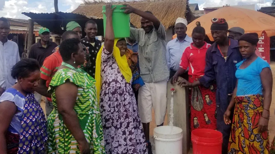 Members of an African community gather around buckets of water