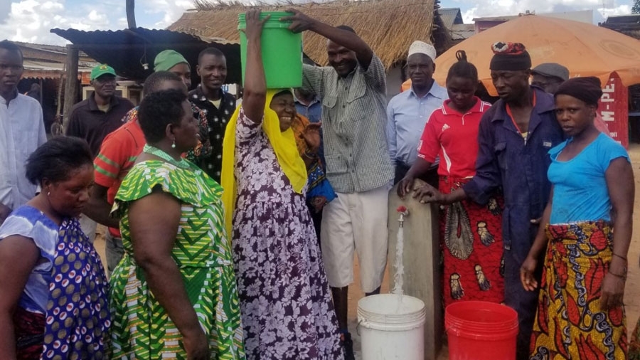 Members of an African community gather around buckets of water