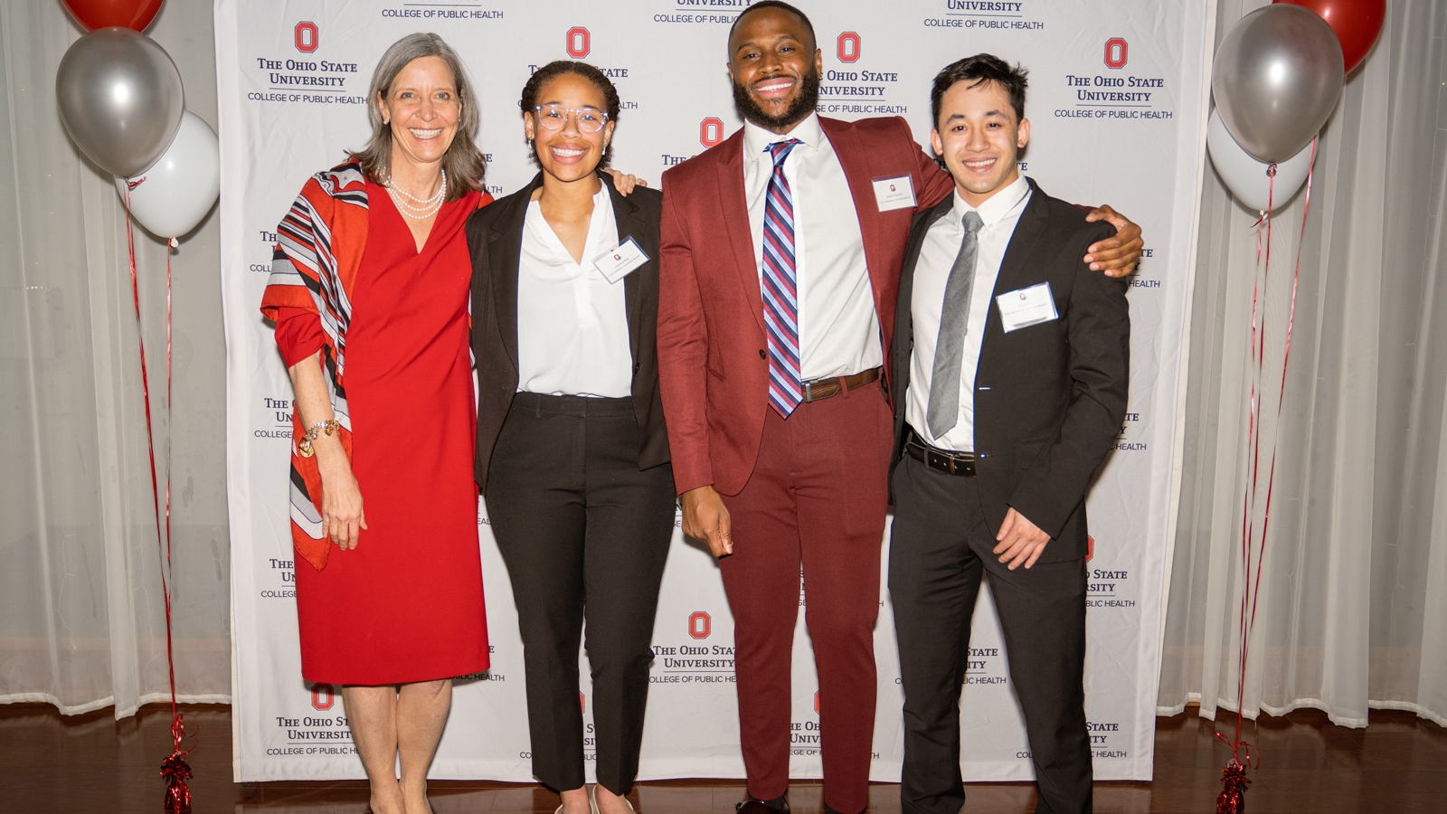 A professor and three MHA students pose for a photo at a college event
