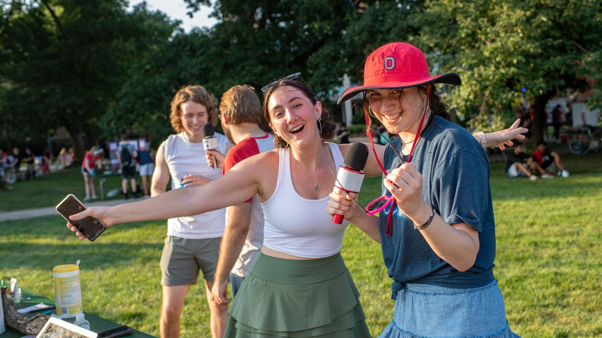 Two smiling women having fun singing during Welcome Week on the Oval at Ohio State