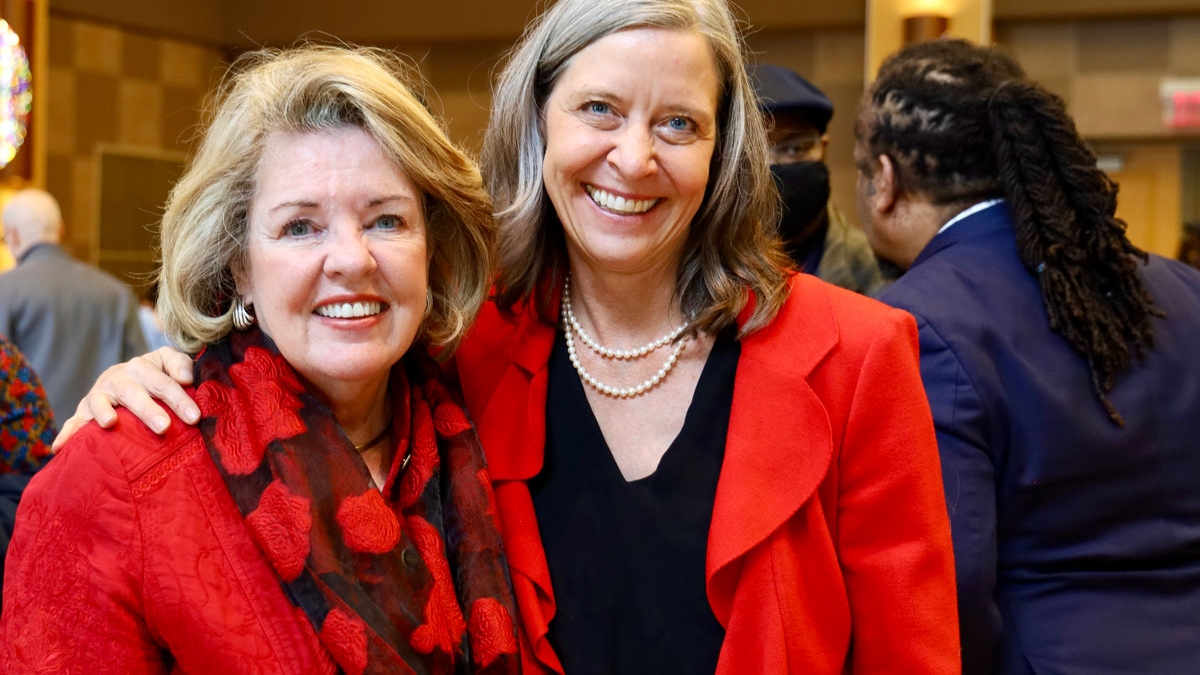 Two smiling women in bright red suit jackets