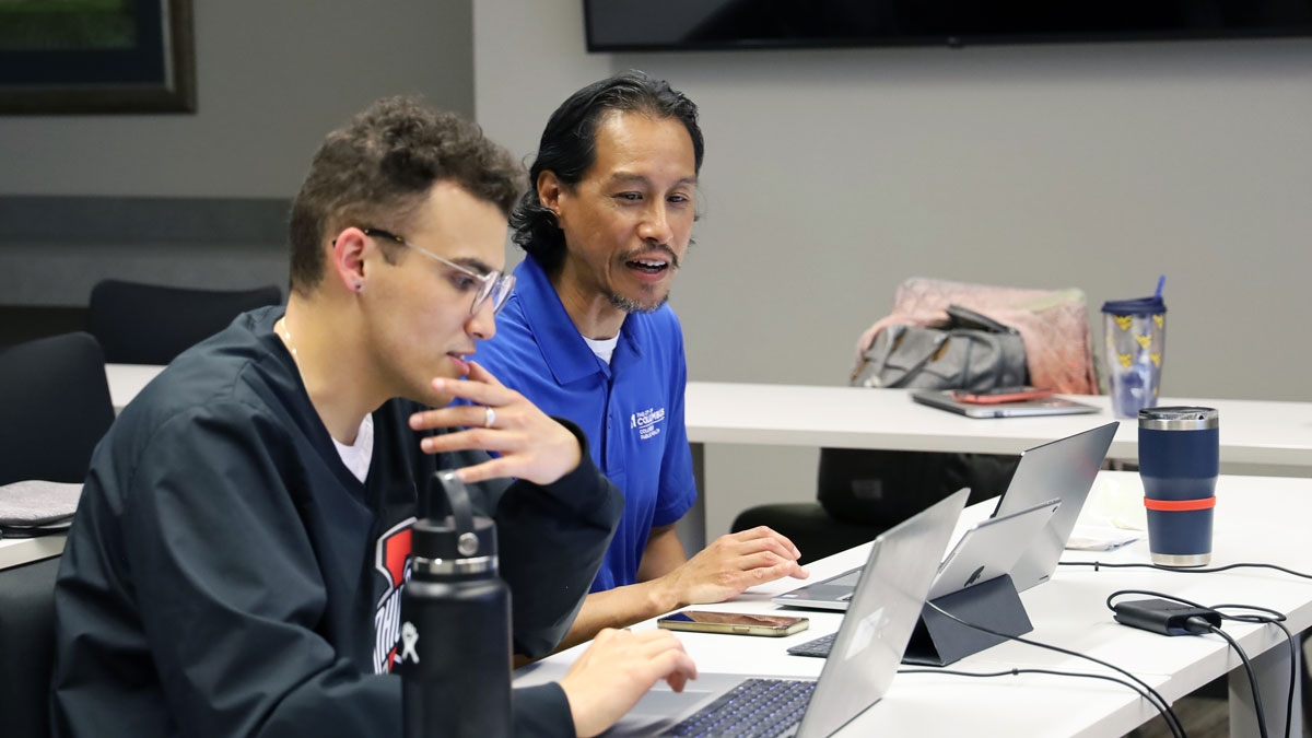 Two public health professionals side by side talk while on their computers