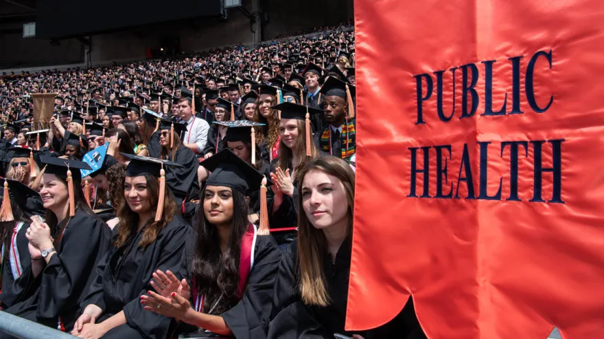 Public Health students attending graduation in Ohio Stadium. A banner with the words "public health" on it is in the foreground