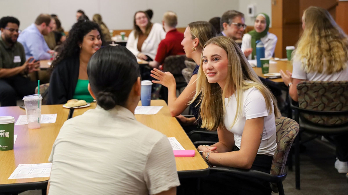 Public health students in a conference room talk during a breakout exercise