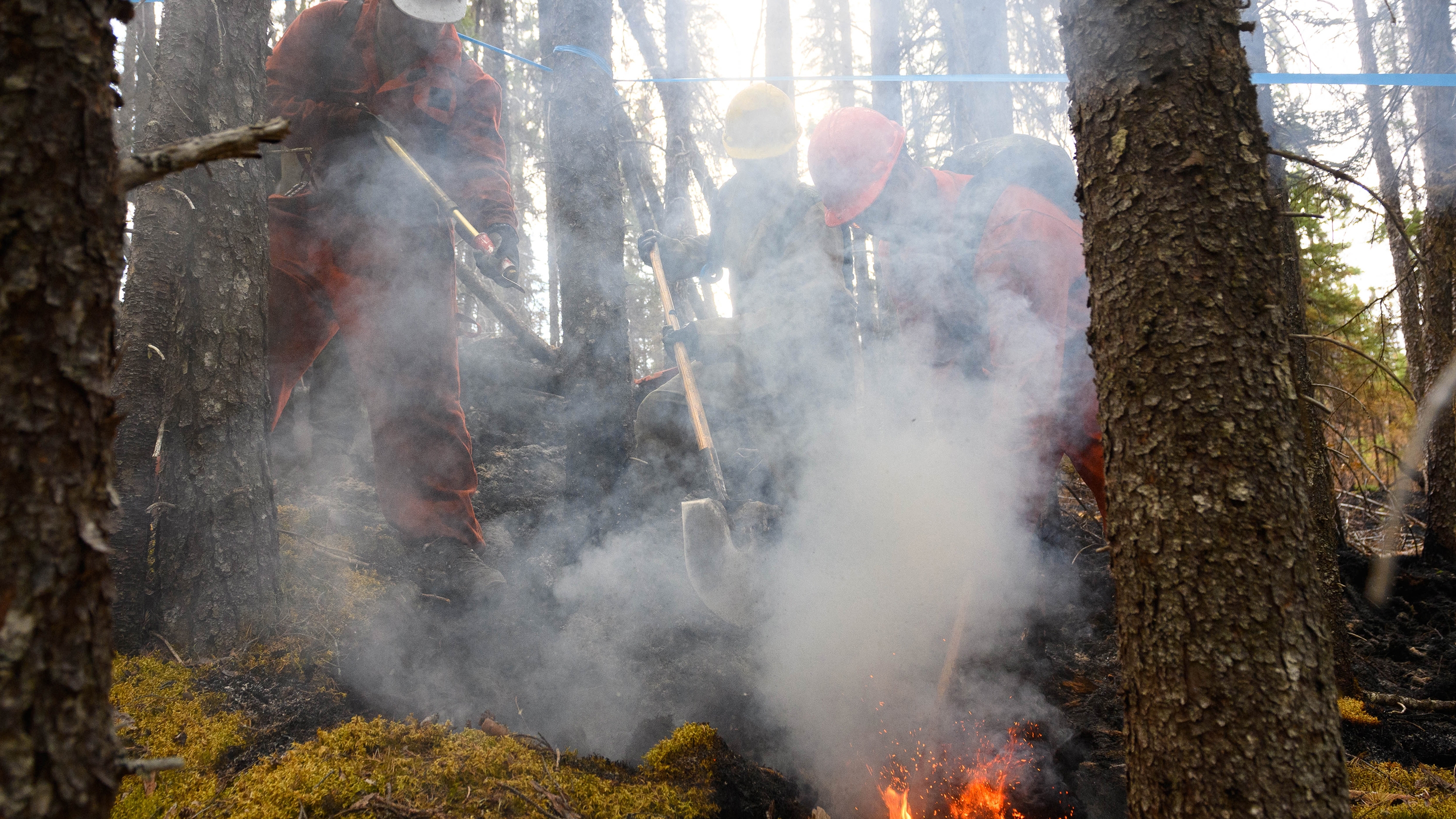 Three people try to put out a wildfire hotspot in Canada.