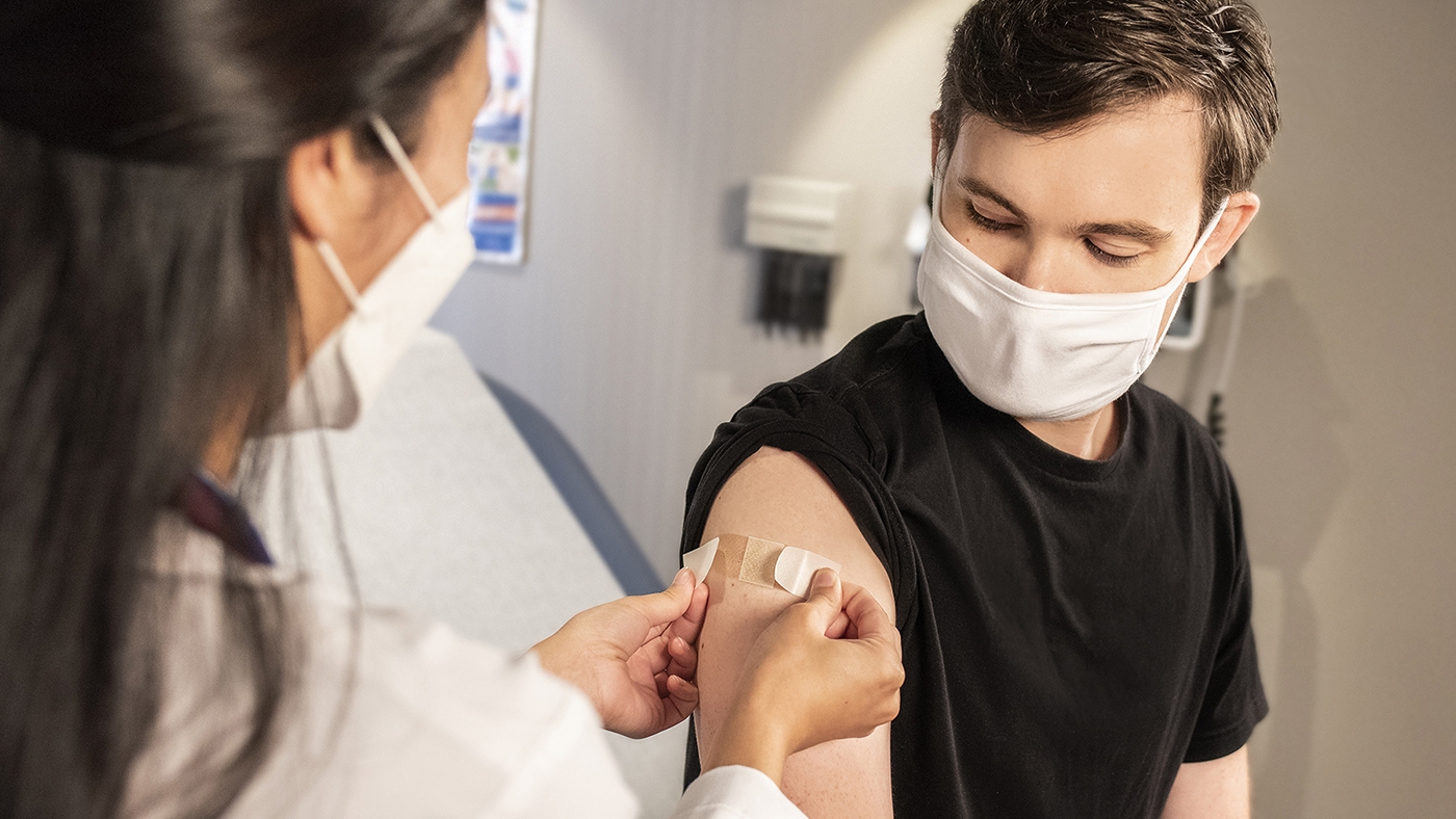 Health care worker places an adhesive bandage on a man's arm.