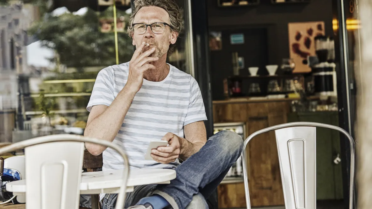 Middle-aged man smoking at an outdoor cafe