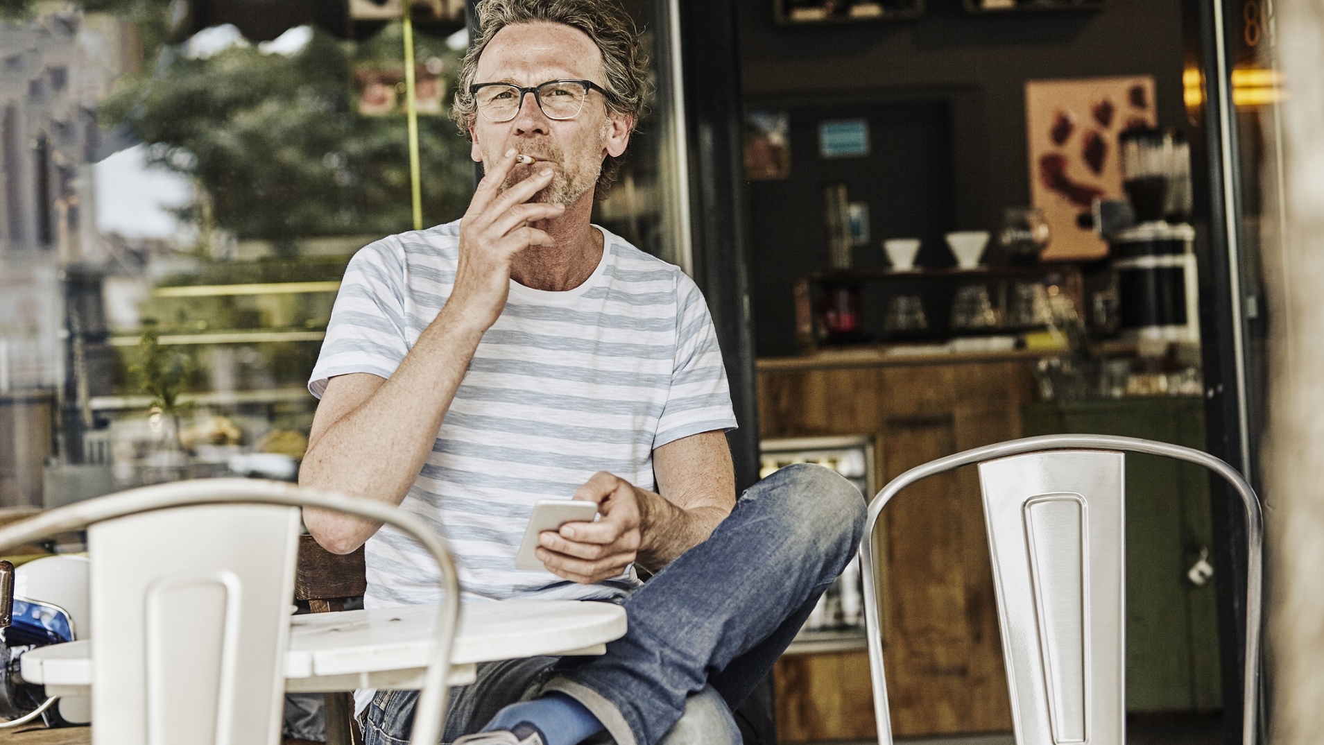 Middle-aged man smoking at an outdoor cafe