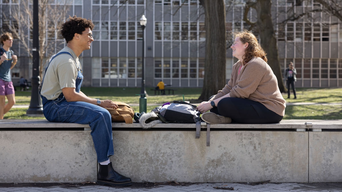 Two Ohio State students sitting on a stone bench on campus talking