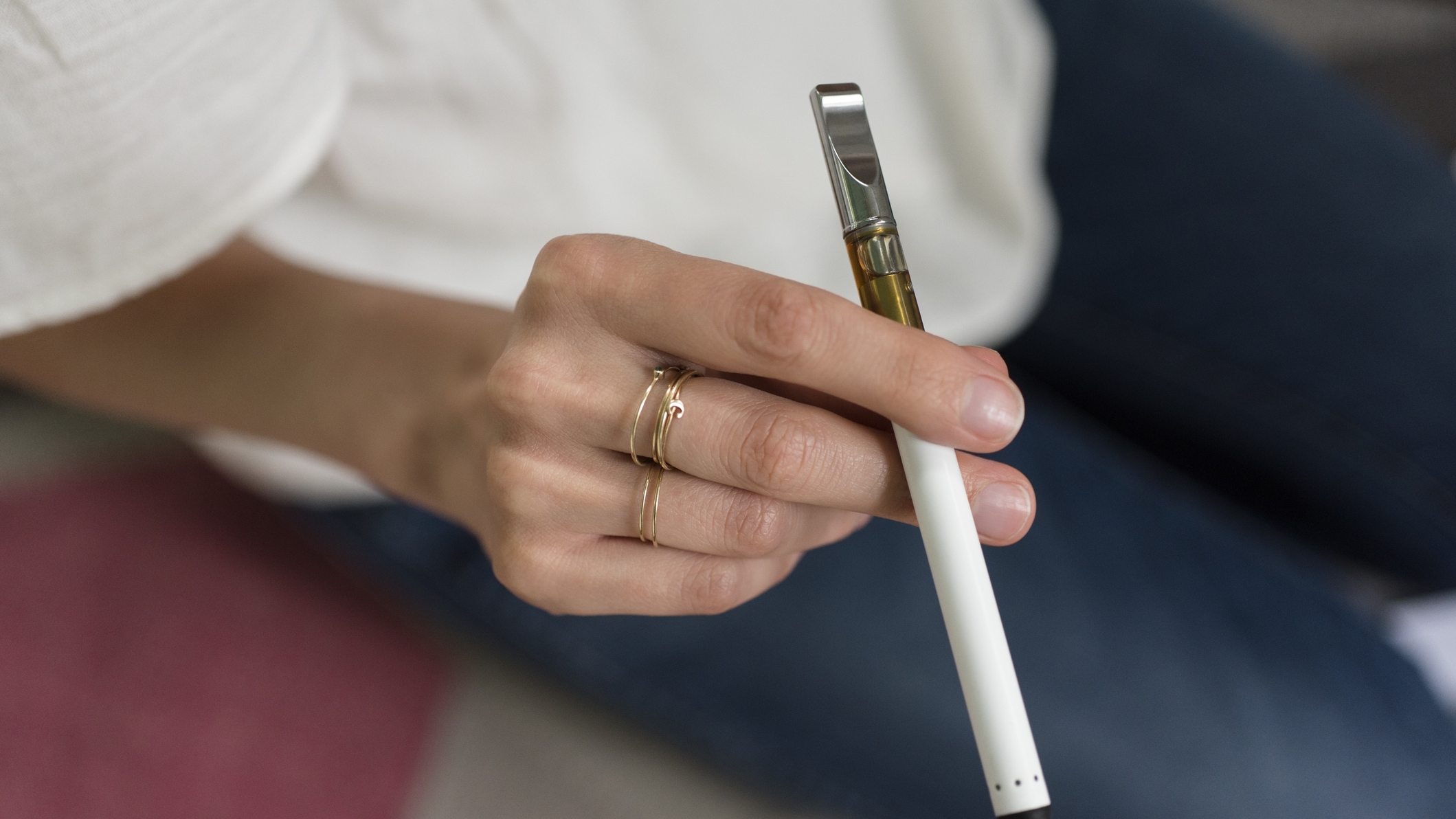 A young woman's hand, holding a vaping device