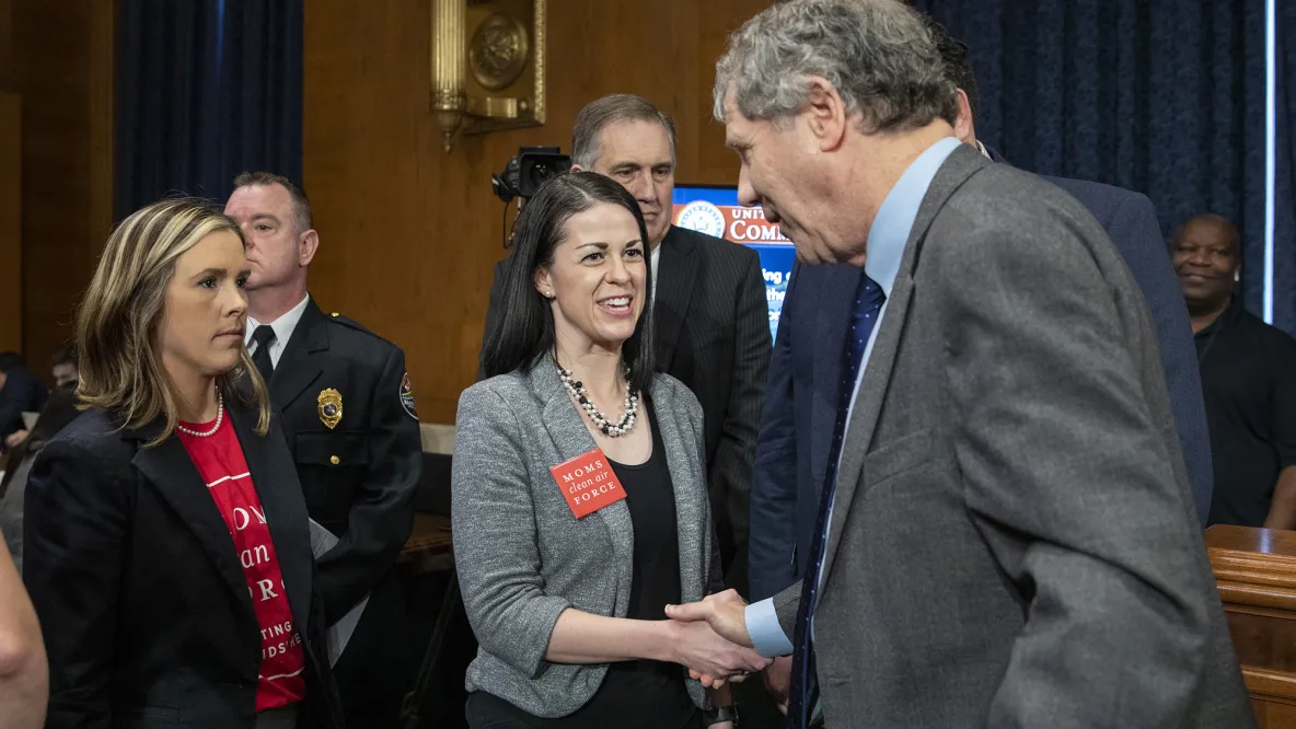 Misti Allison shakes hands with Sherrod Brown in a government setting.