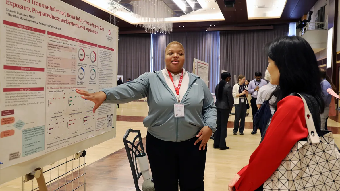 Sharefa Duhaney points at her research poster while Dean Paula Song listens