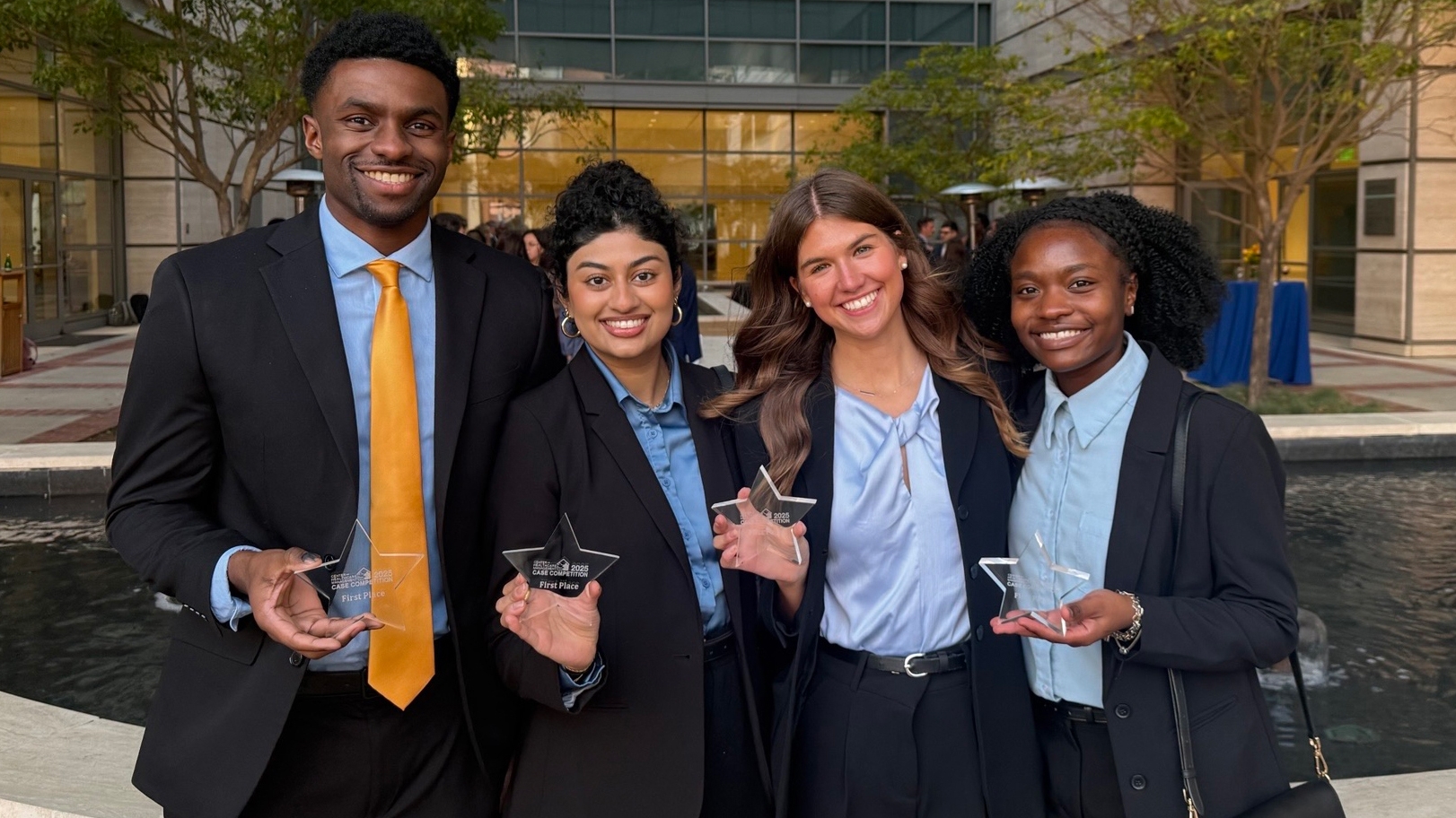 Four students pose holding awards.