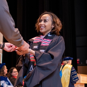 Young woman at public health receives CPH medallion at precommencement ceremony