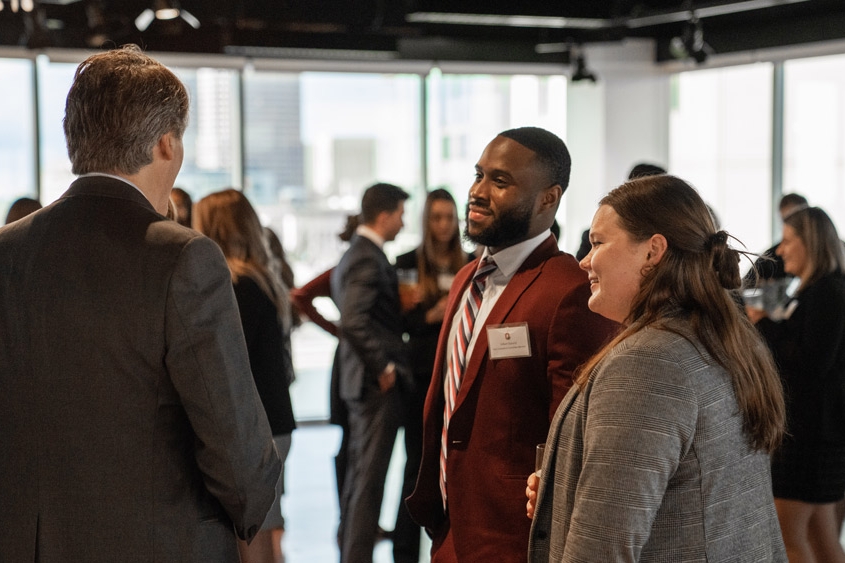 Two MHA students network with a health administration professional