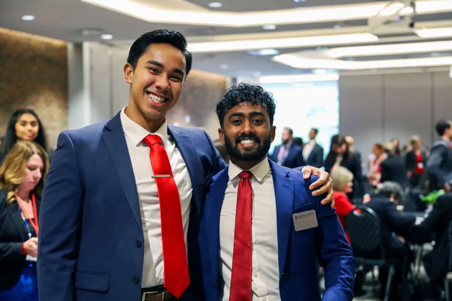 Two Master of Health Administration students in blue suits and red ties
