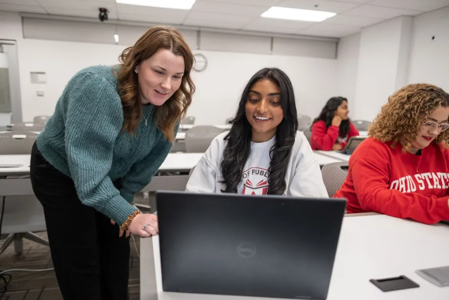 a professor pointing to the screen of a student's laptop