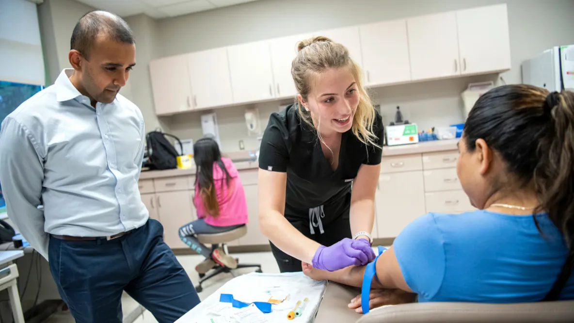 A public health nurse performs a test on a patient while a health care leader looks on