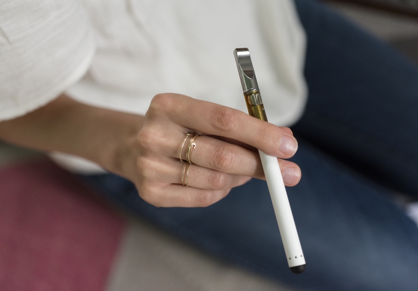 A young woman's hand, holding a vaping device