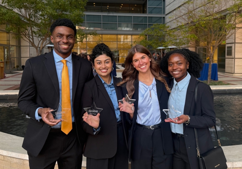 Four students pose holding awards.