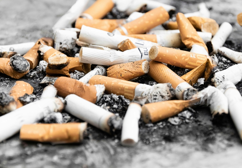 A pile of used cigarettes and ash on the ground.