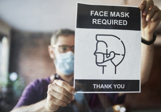 Man posting a sign that says masks are required