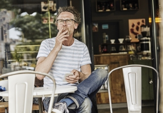 Middle-aged man smoking at an outdoor cafe