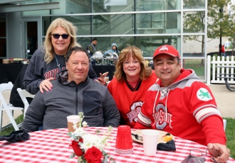 Four people pose for a photo at the CPH Homecoming tailgate
