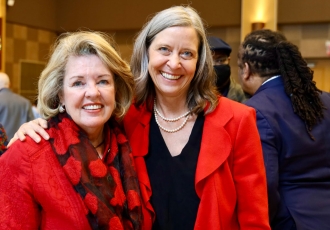 Two smiling women in bright red suit jackets