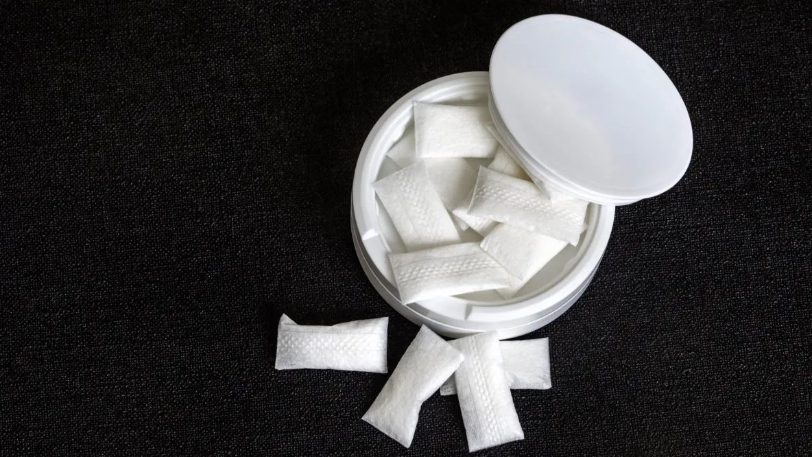 A black background with a white tin full of white nicotine pouches