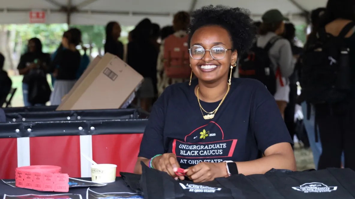 College student works at a table for their student organization at a university event